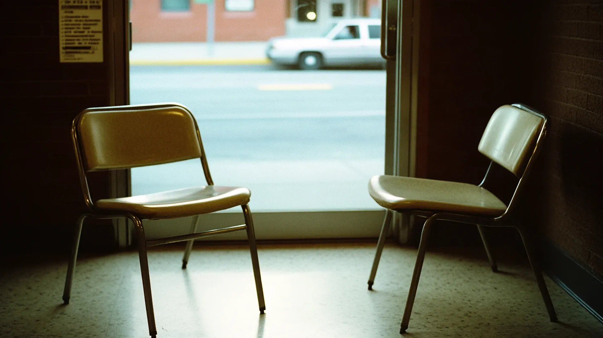 Two empty waiting-room chairs by a window