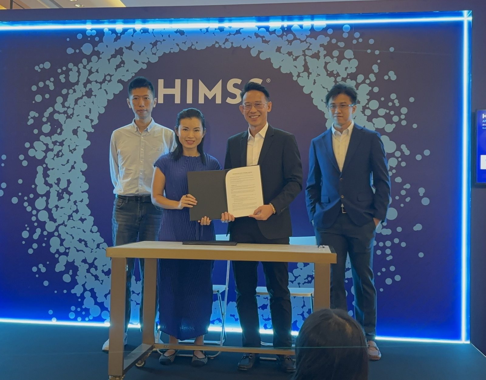 Rezonate and Stellaris Robotics representatives holding the signed MOU on the HIMSS APAC 2026 stage